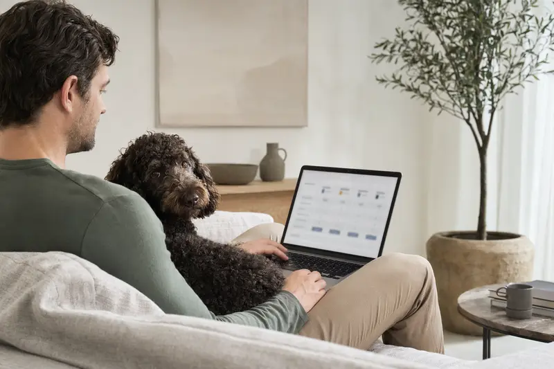 Ein Hund und sein Besitzer sitzen gemütlich auf dem Sofa, während sie eine Versicherungsvergleichsseite auf dem Laptop betrachten.
