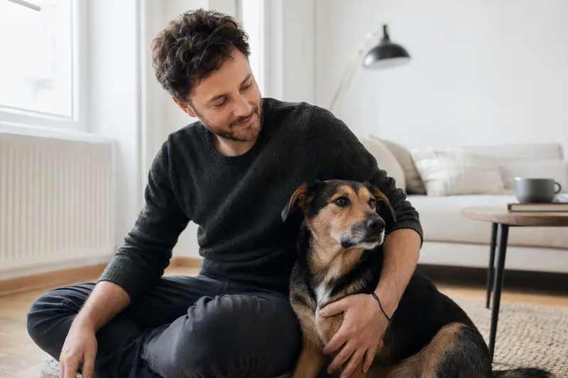 Ein entspannter Hund sitzt neben seinem Besitzer in einer hellen, modernen Wohnung.
